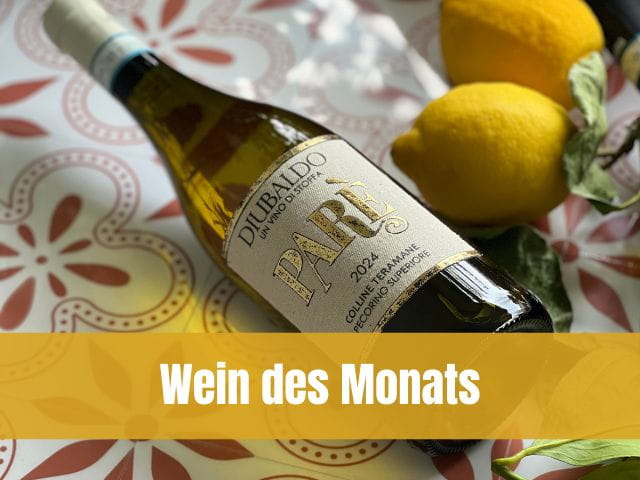 Flasche Weisswein Paré Pecorino d'Abruzzo neben frischen Zitronen auf dekorativem Untergrund, mit gelbem Banner „Wein des Monats“.