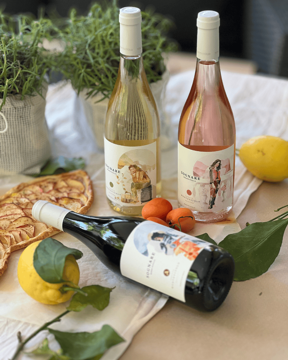 Set „Sognare“ mit sechs Weinen aus Apulien: Weißwein, Rosé und Rotwein, dekoriert mit Zitronen, Aprikosen und einer Obsttarte auf einem sommerlichen Tisch.